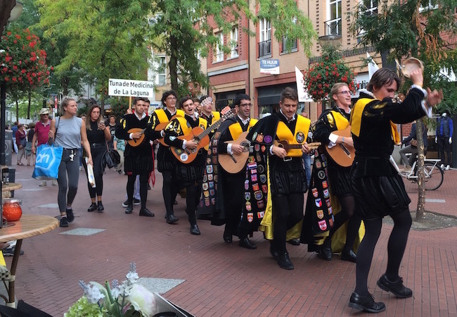 Muziekgroepen trekken zingend door de Nieuwstraat tijdens de Pasa calles van het Tuna Festival in Eindhoven