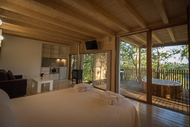 Deze boomhut in Galicië heeft een bed, zithoek, keukentje en kachel in een grote ruimte.