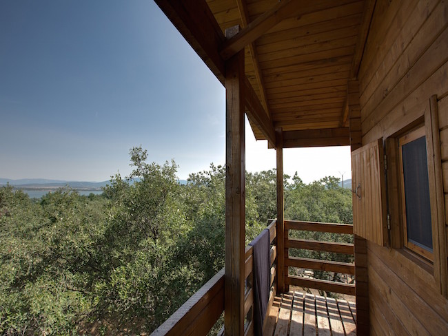 Vanuit de boomhutten van Ecolodge Cabañeros kijk je uit over eeuwenoude Mediterrane bossen en het Torre de Abraham stuwmeer