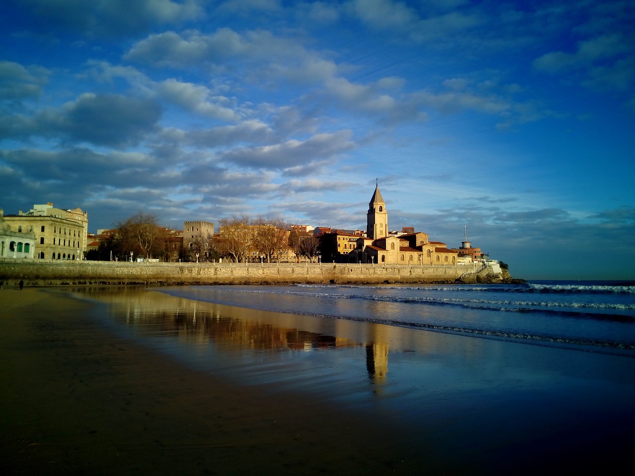 San Lorenzo strand in Gijón met op achtergrond San Pedro kerk